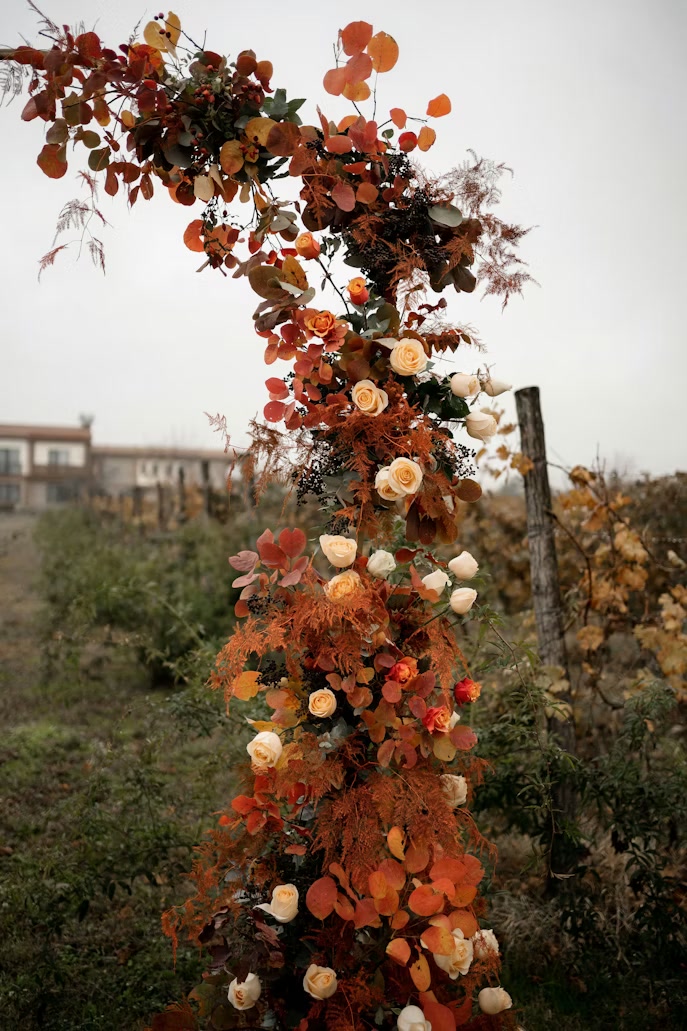A candlelit autumn tablescape in burgundy and brass under vines.