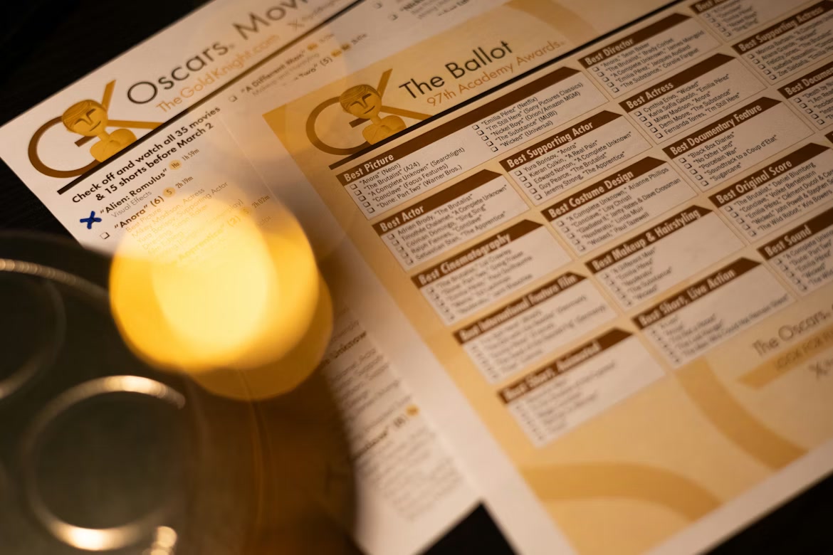 A gold Academy Award statuette beneath warm stage light.
