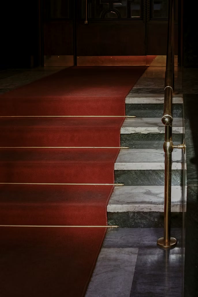 A red carpet lined with velvet stanchions and soft press light.