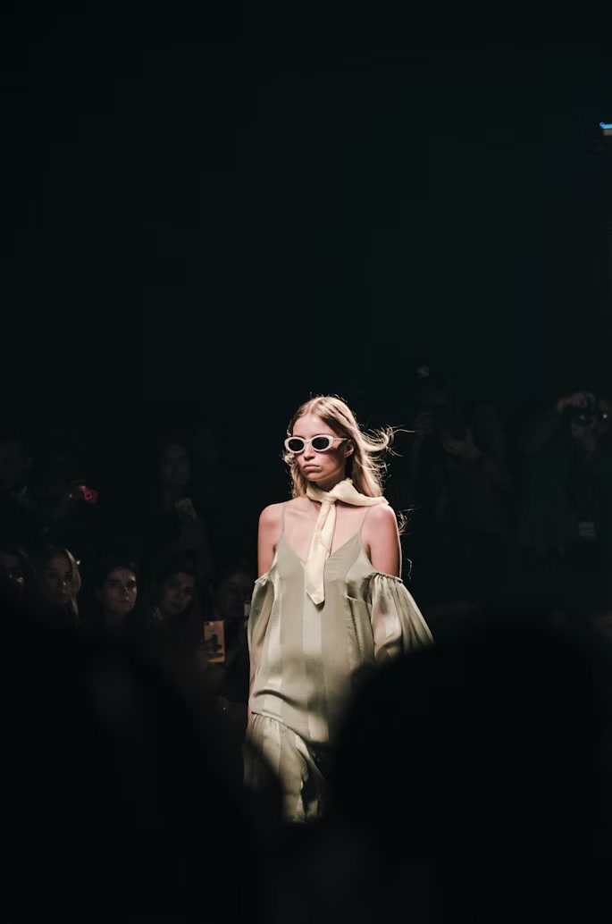 A model walking a dimly lit couture runway.
